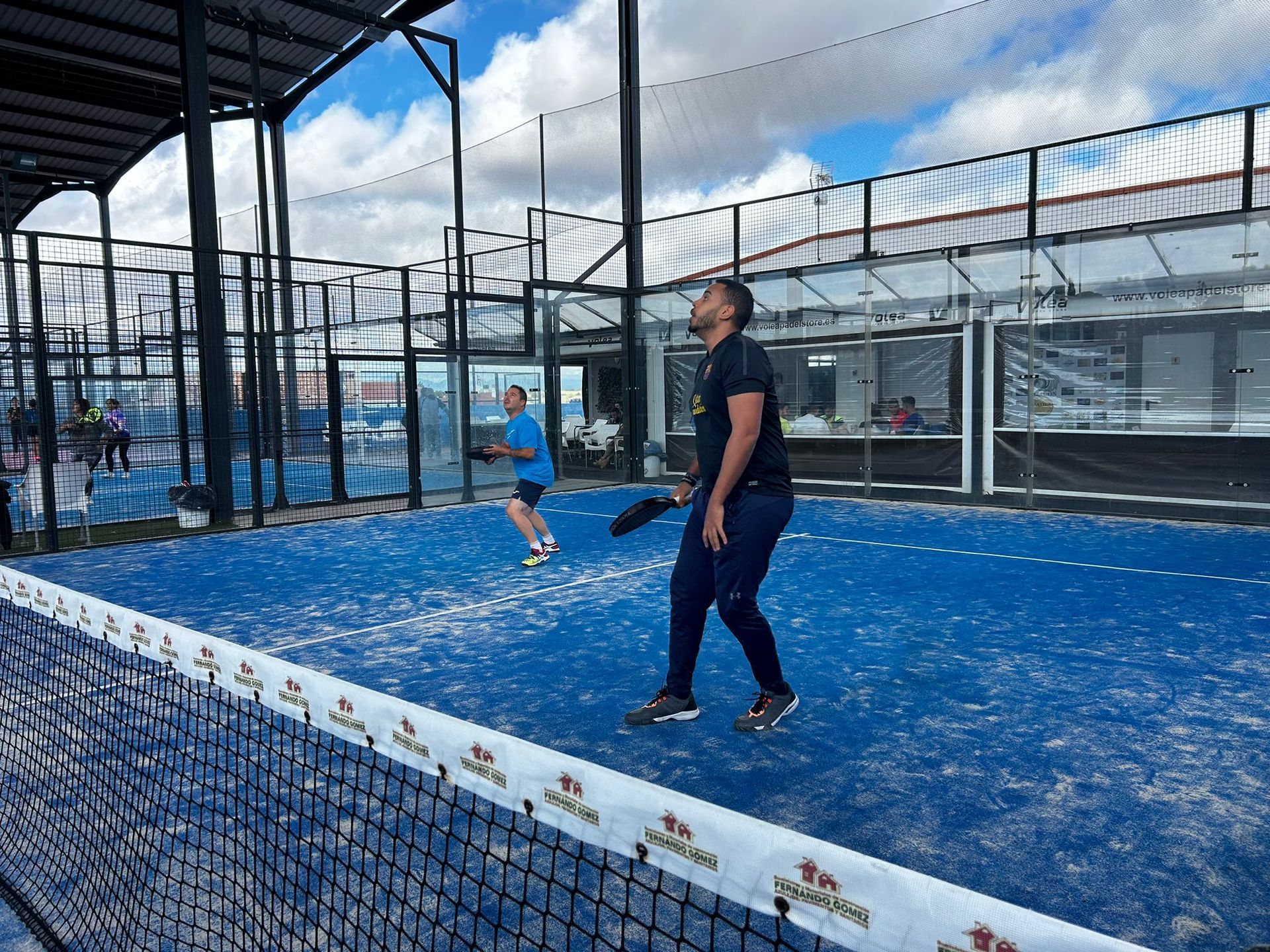 Un hombre está jugando al pádel en una cancha azul.