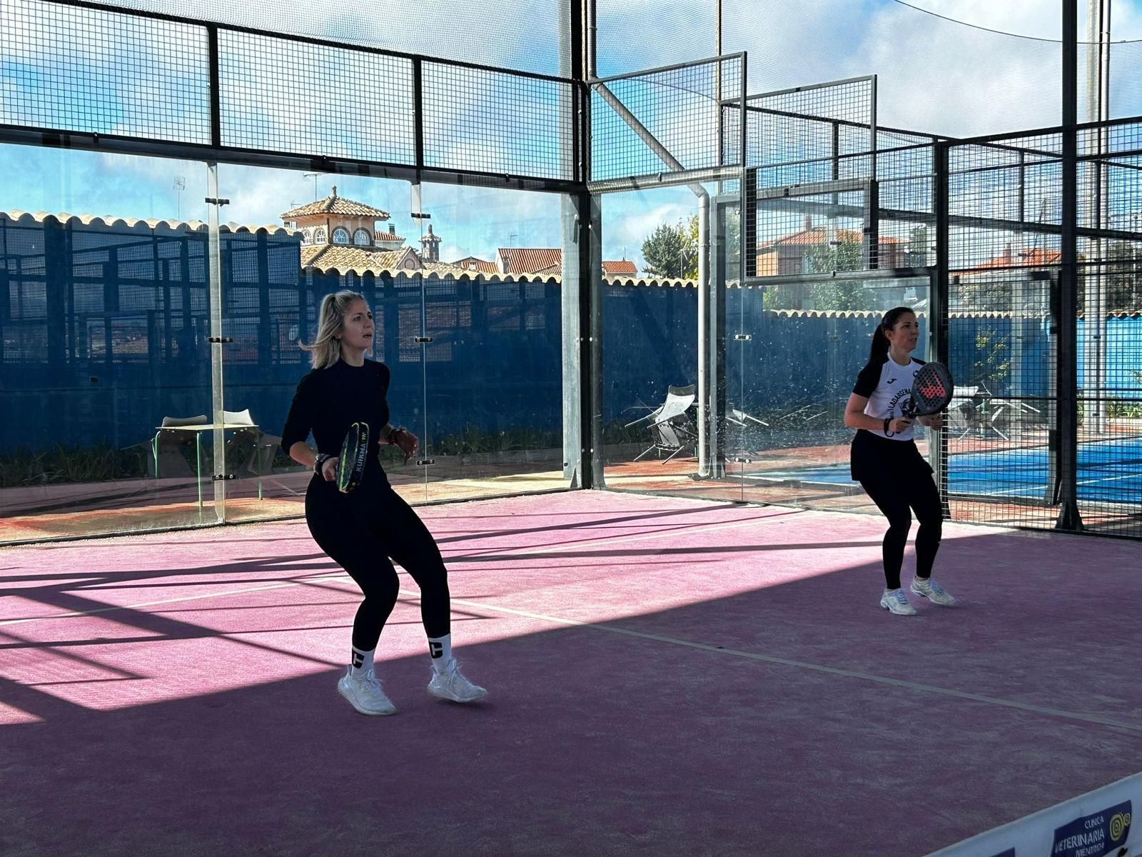 Dos mujeres están jugando al pádel en una cancha.