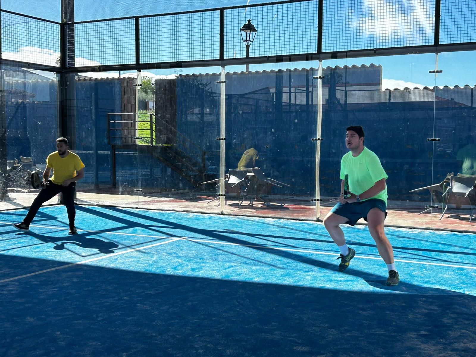Dos hombres están jugando al pádel en una cancha azul.
