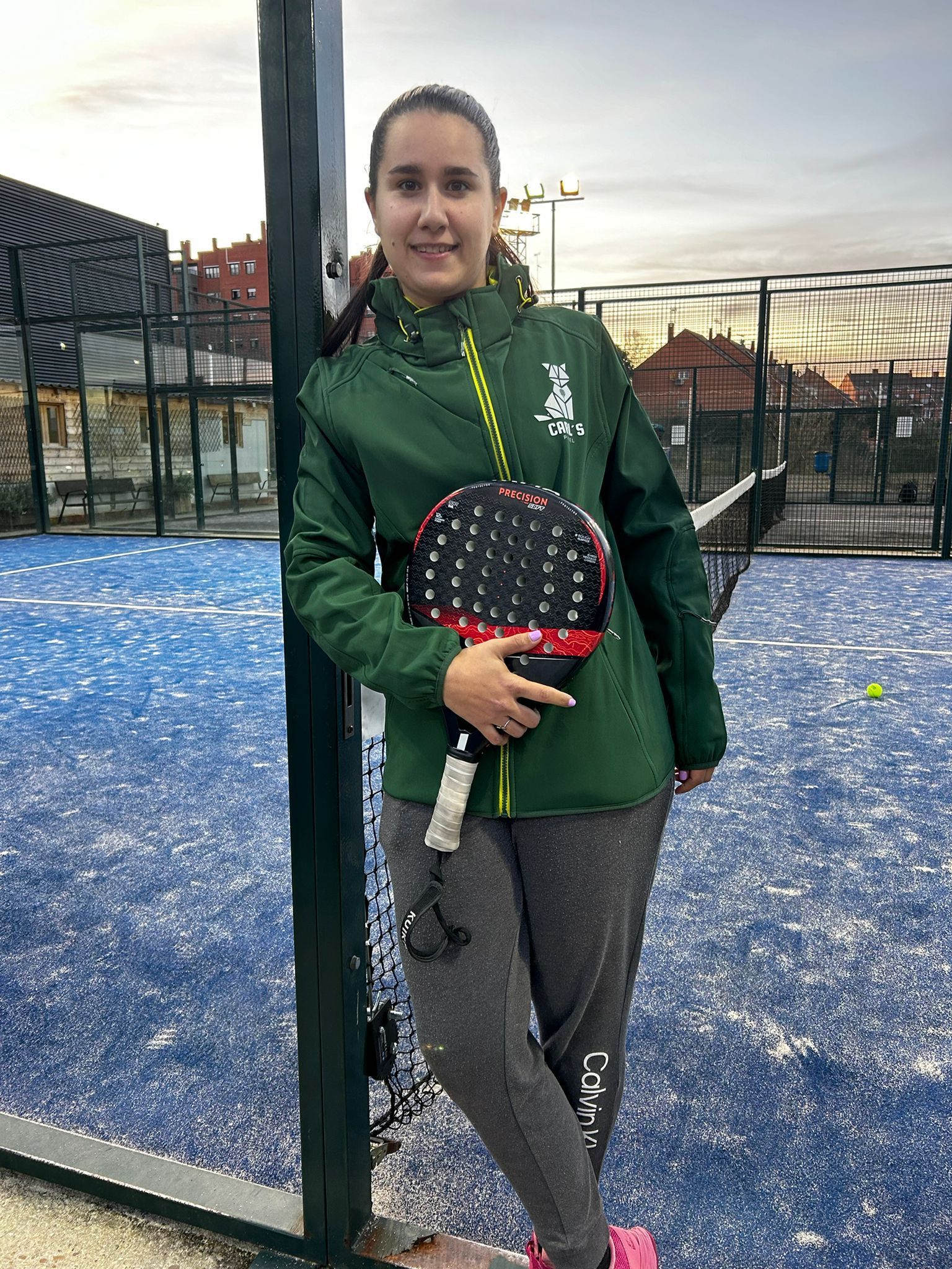 Una niña está parada en una cancha de pádel sosteniendo una raqueta de pádel.