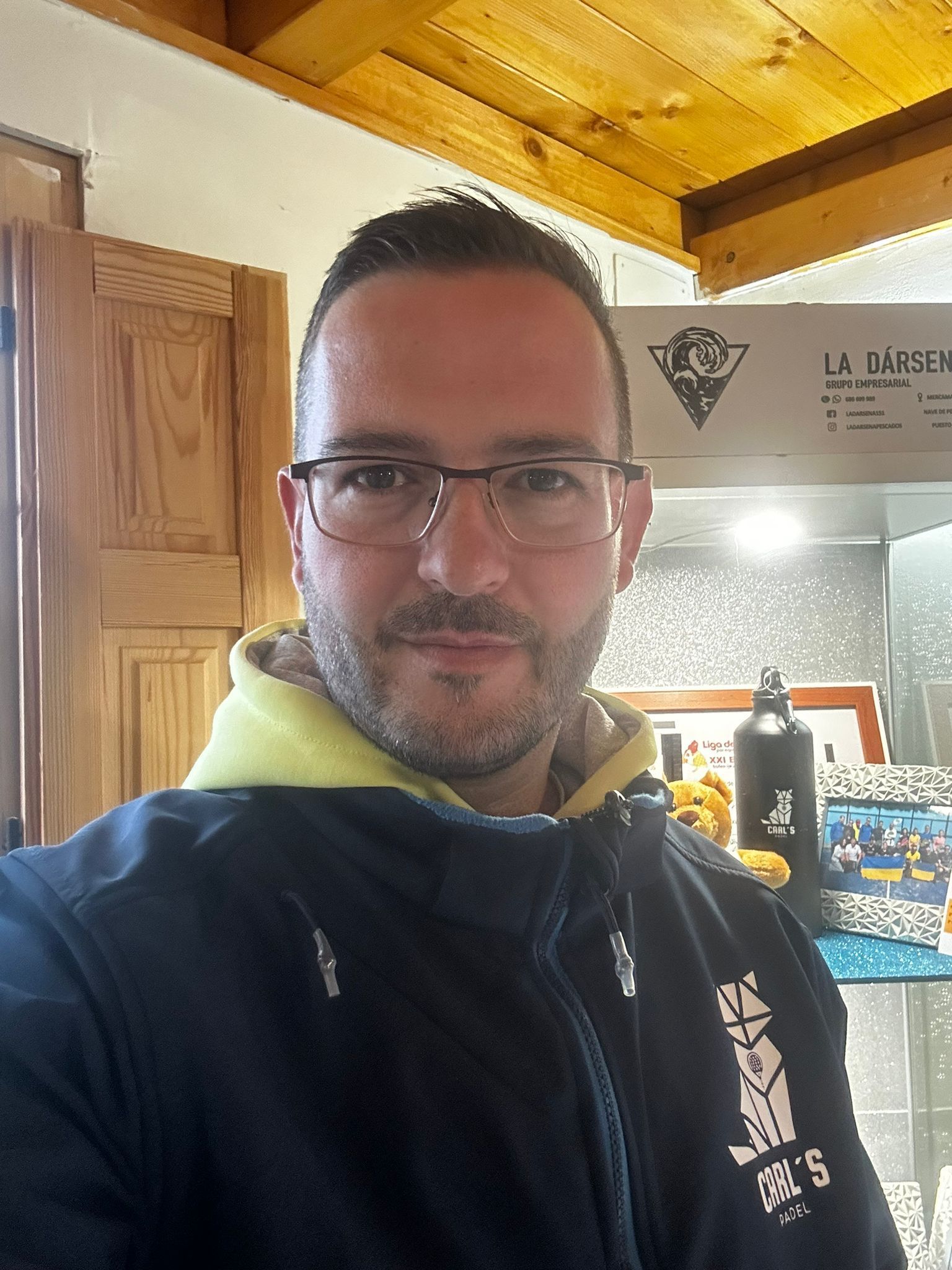 Un hombre que lleva gafas y una chaqueta negra se está tomando un selfie en una cocina.
