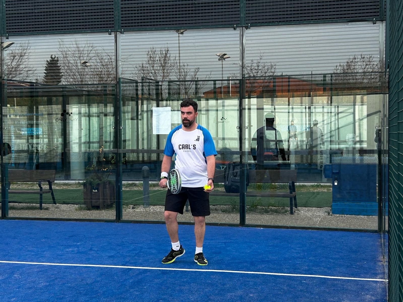 Un hombre está jugando al pádel en una cancha azul.