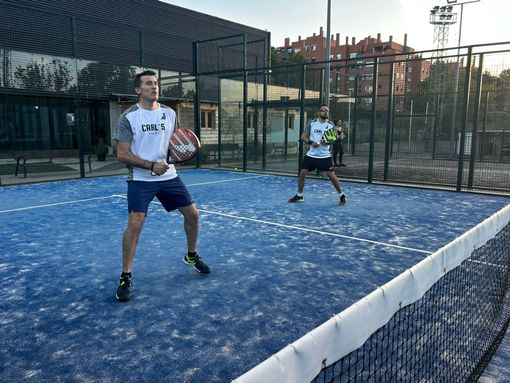 Dos hombres están jugando al pádel en una cancha.