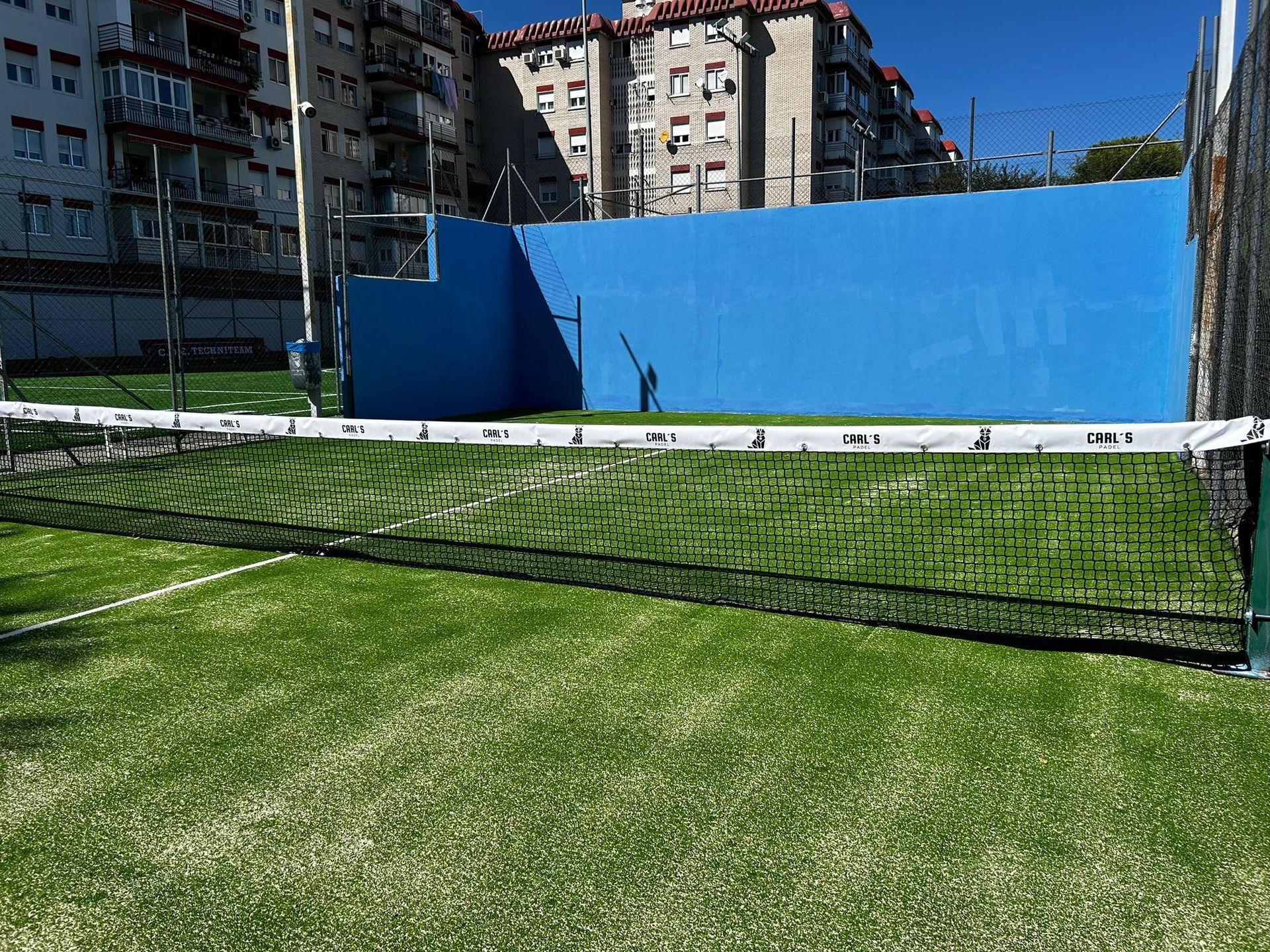 Una red de tenis se encuentra encima de una exuberante cancha de tenis verde.