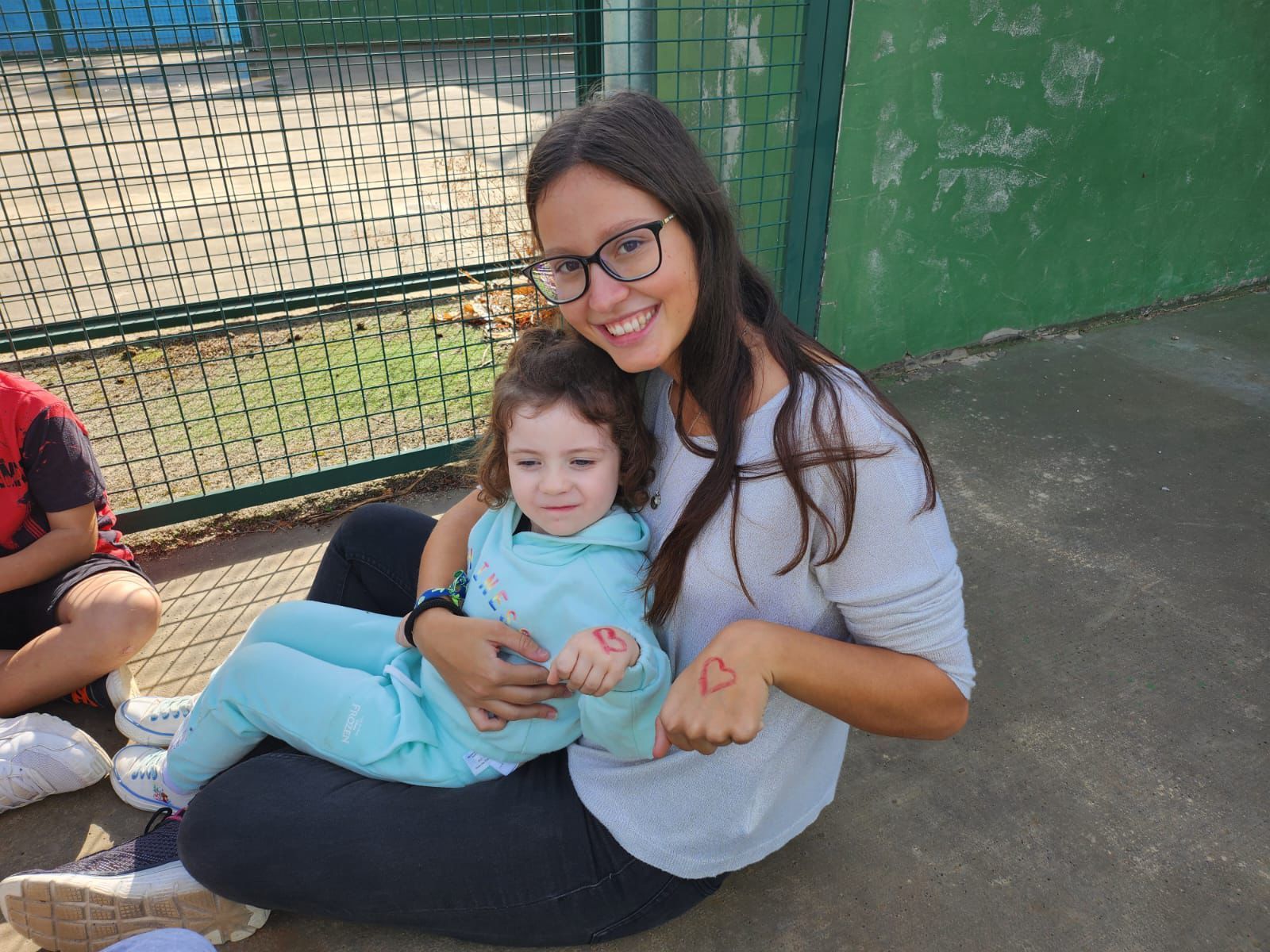 Una mujer está sentada en el suelo sosteniendo a una niña en sus brazos.