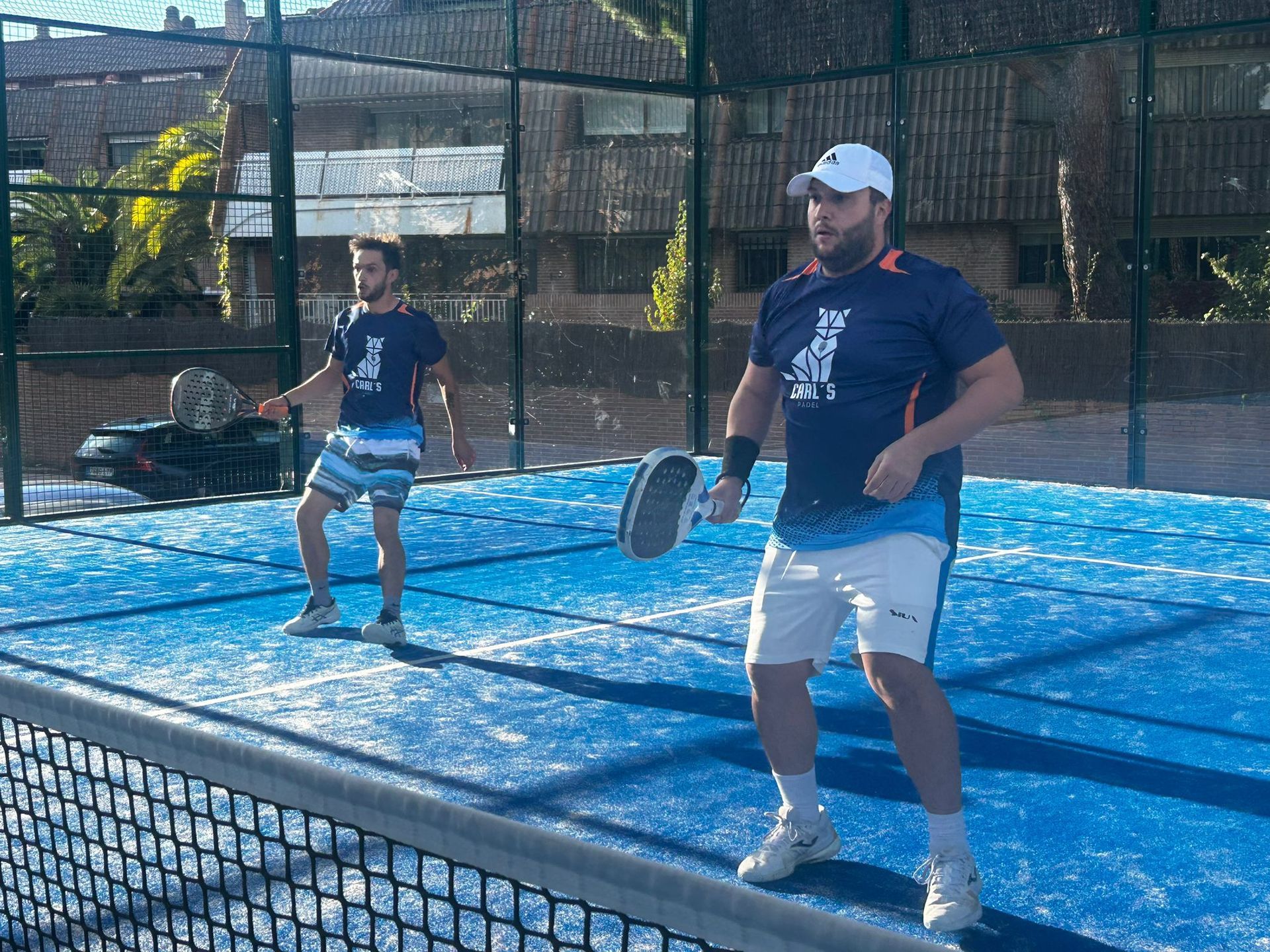 Dos hombres están jugando al pádel en una cancha azul