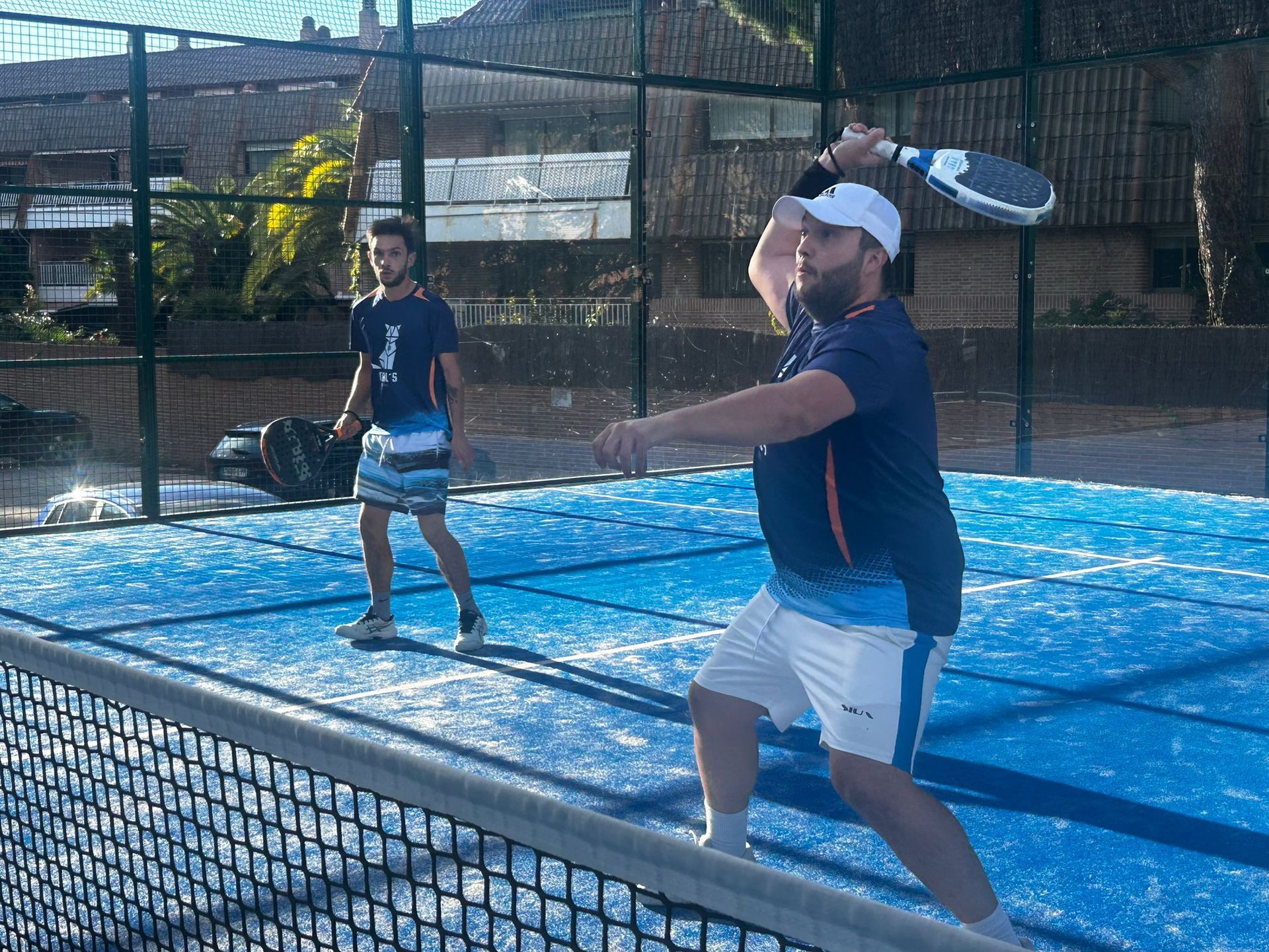 Dos hombres están jugando al tenis en una cancha azul.