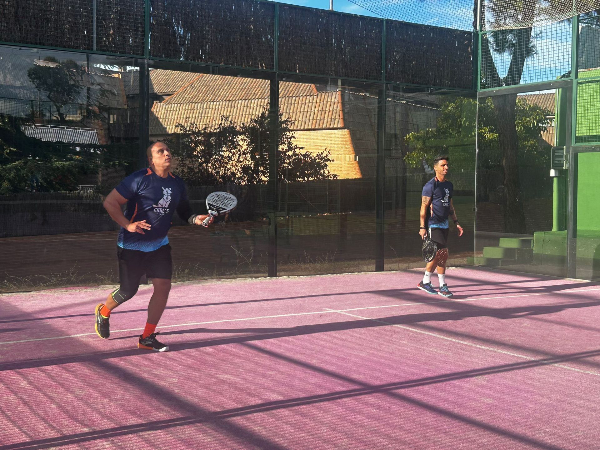 Dos hombres están jugando al pádel en una cancha rosa.