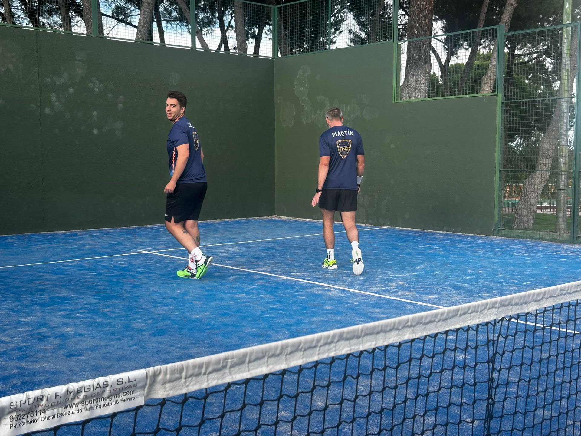 Dos hombres están jugando al tenis en una cancha azul.