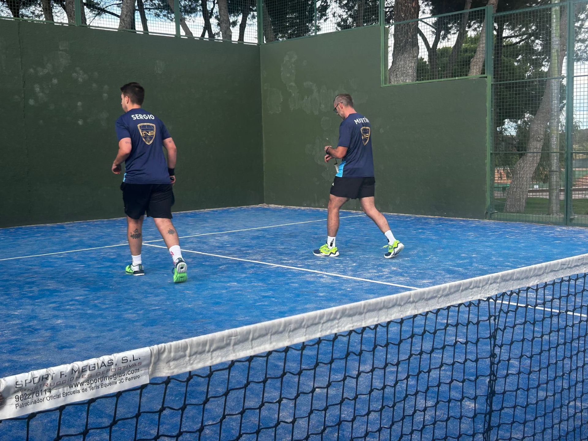 Dos hombres están jugando al tenis en una cancha azul.