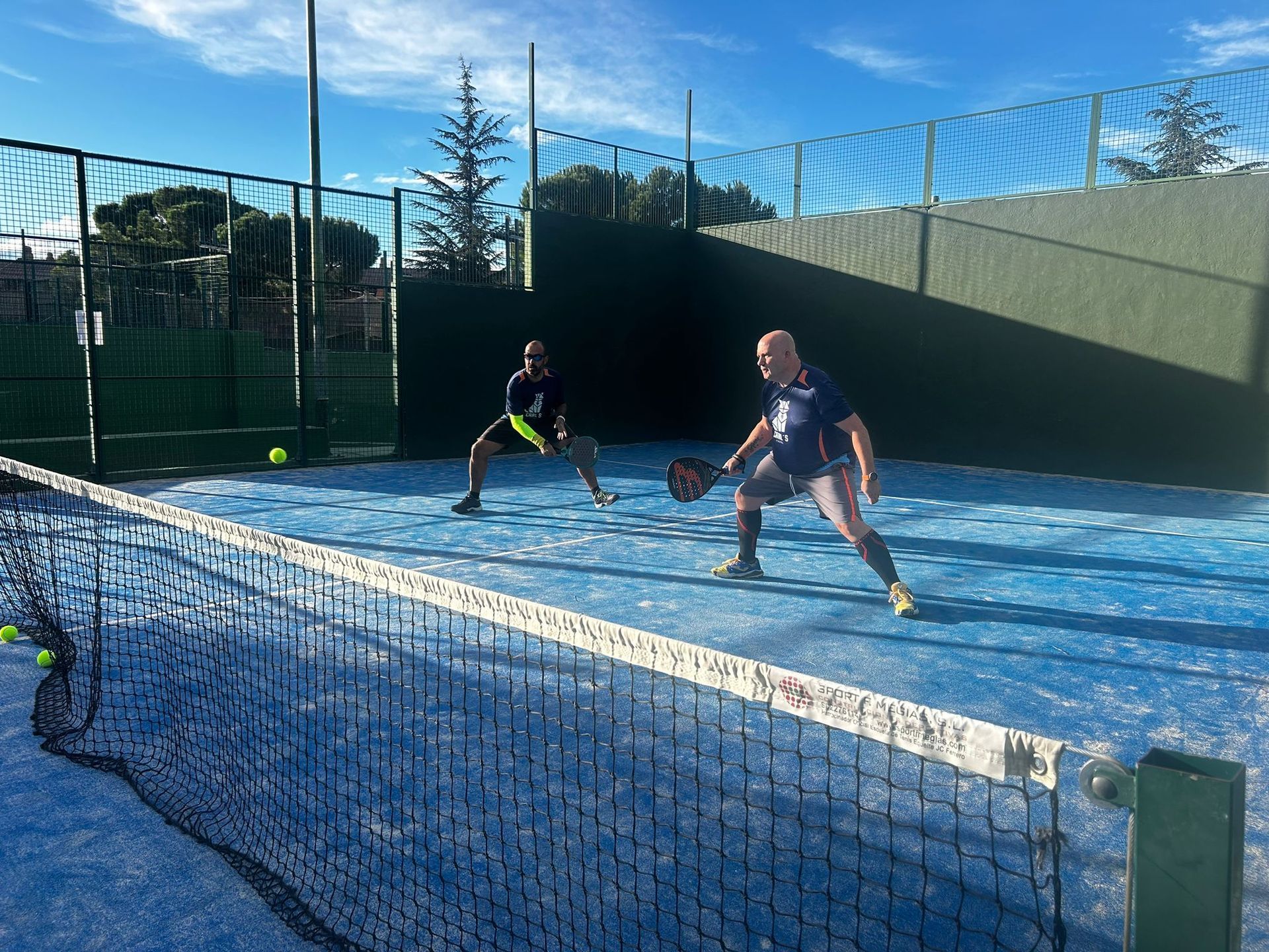 Dos hombres están jugando al pádel en una cancha azul.