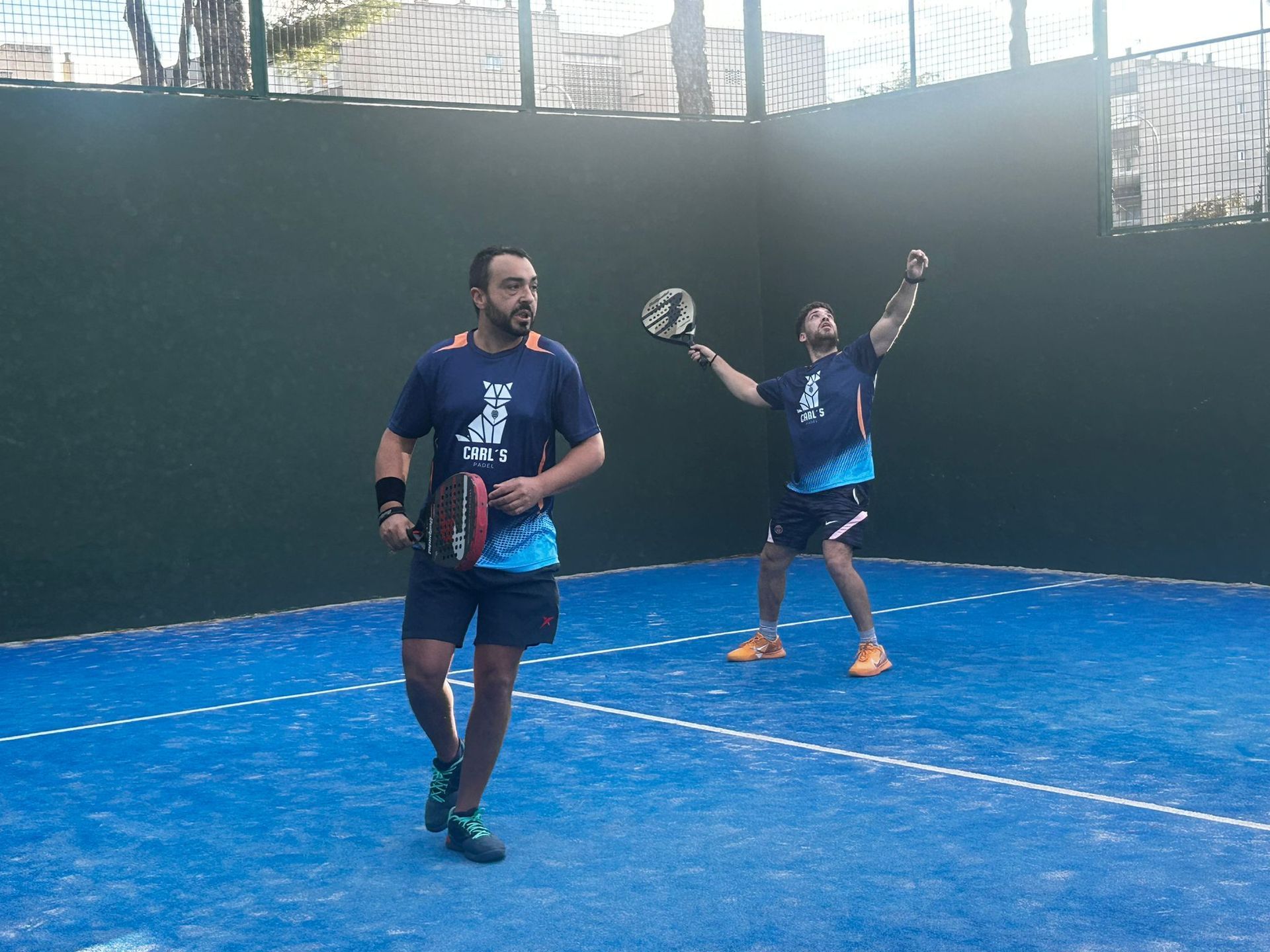 Dos hombres están jugando al pádel en una cancha azul.