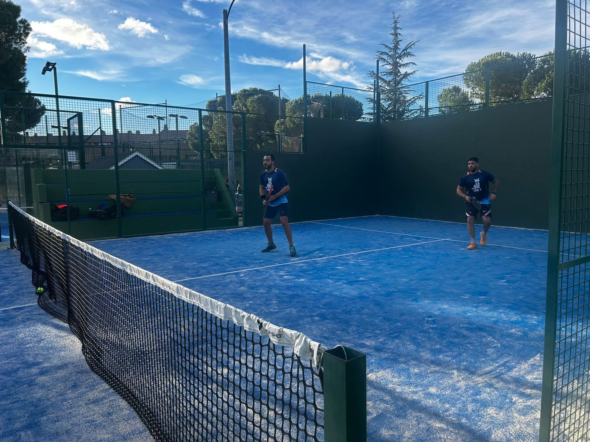 Dos hombres están jugando al pádel en una cancha azul.