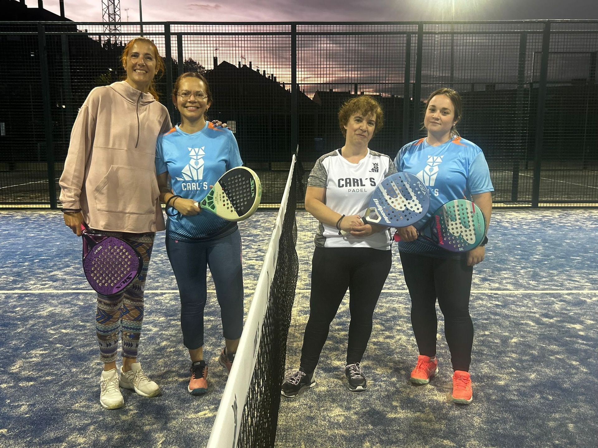 Un grupo de mujeres posa para una fotografía en una cancha de tenis.