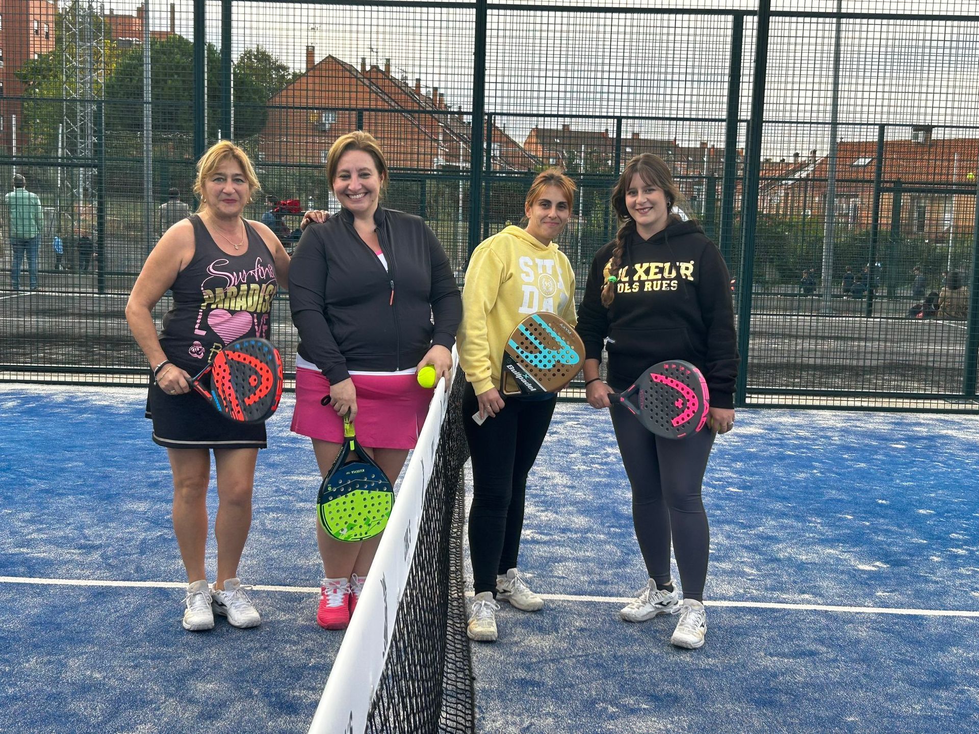 Un grupo de mujeres están de pie en una cancha de tenis sosteniendo raquetas de tenis.