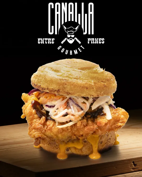 Un sándwich de pollo frito con ensalada de col y queso sobre una galleta sobre una tabla de cortar de madera.