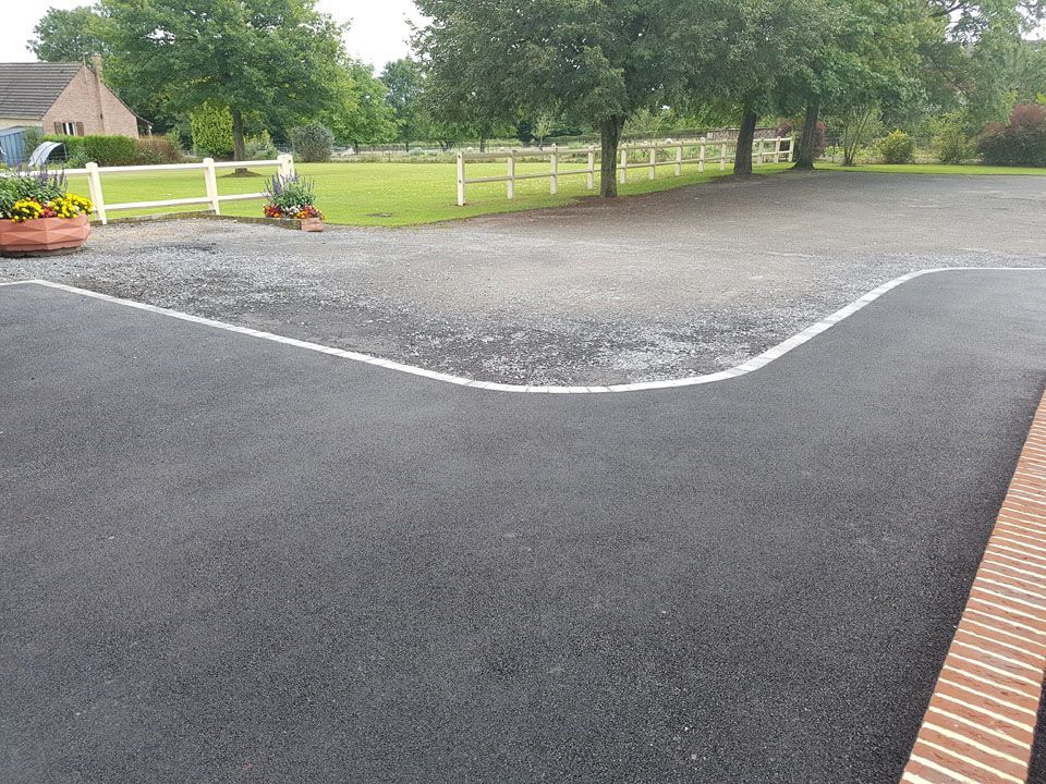 Cour en enrobé à côté d'un grand jardin