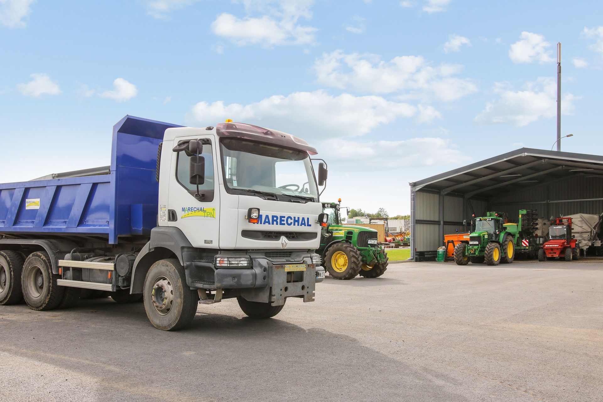 Entrée de l'entrepôt avec un camion et des tracteurs
