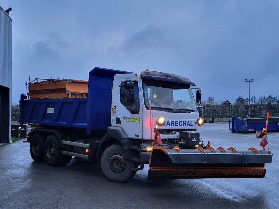 Camion de salage qui sale une route enneigée
