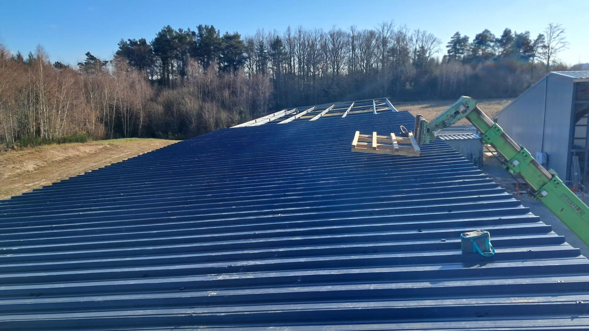 Bâtiment au toit sombre et aux murs de pierre, avec des plantes devant.