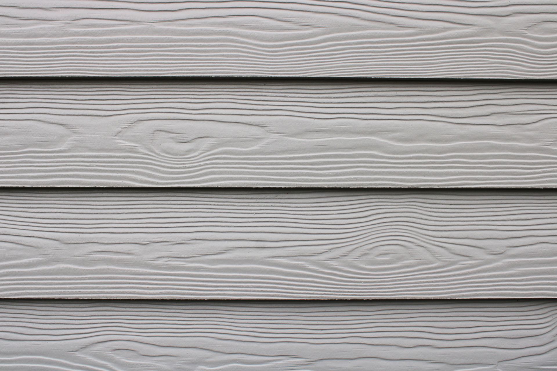 Bardage gris imitation bois à planches horizontales laissant apparaître le grain.