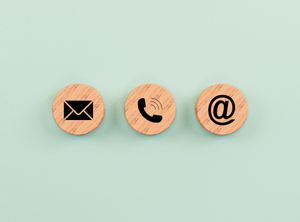 Cercles en bois ornés d'icônes : enveloppe, téléphone et arobase.