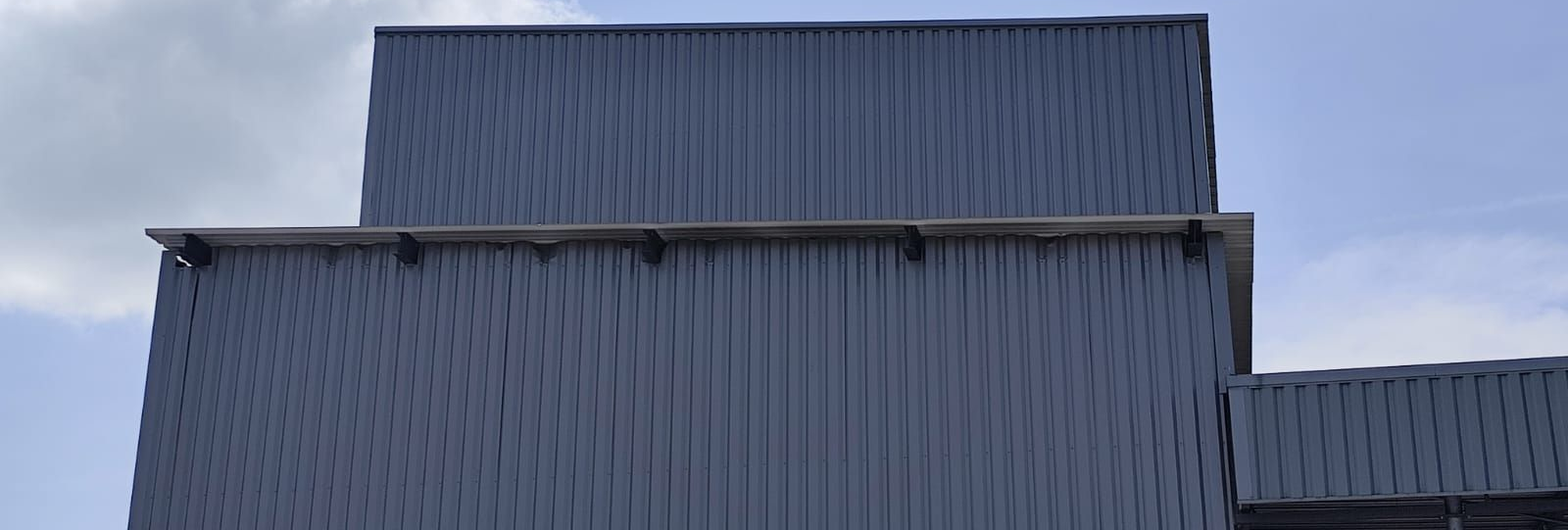 Bâtiment en tôle ondulée grise.