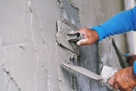 Ein Mann verputzt eine Wand mit einer Kelle.