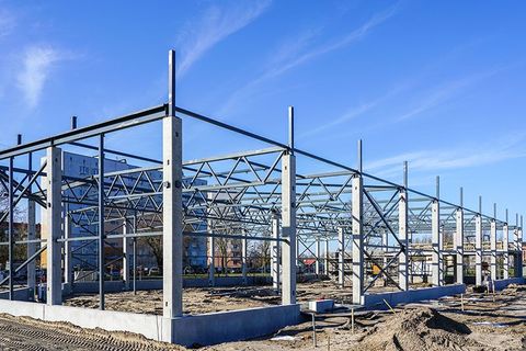 Auf einem Feld aus Erde wird eine große Metallkonstruktion errichtet.