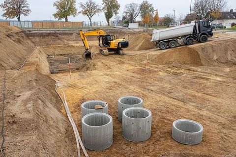 Eine Baustelle mit Betonringen und einem Muldenkipper.