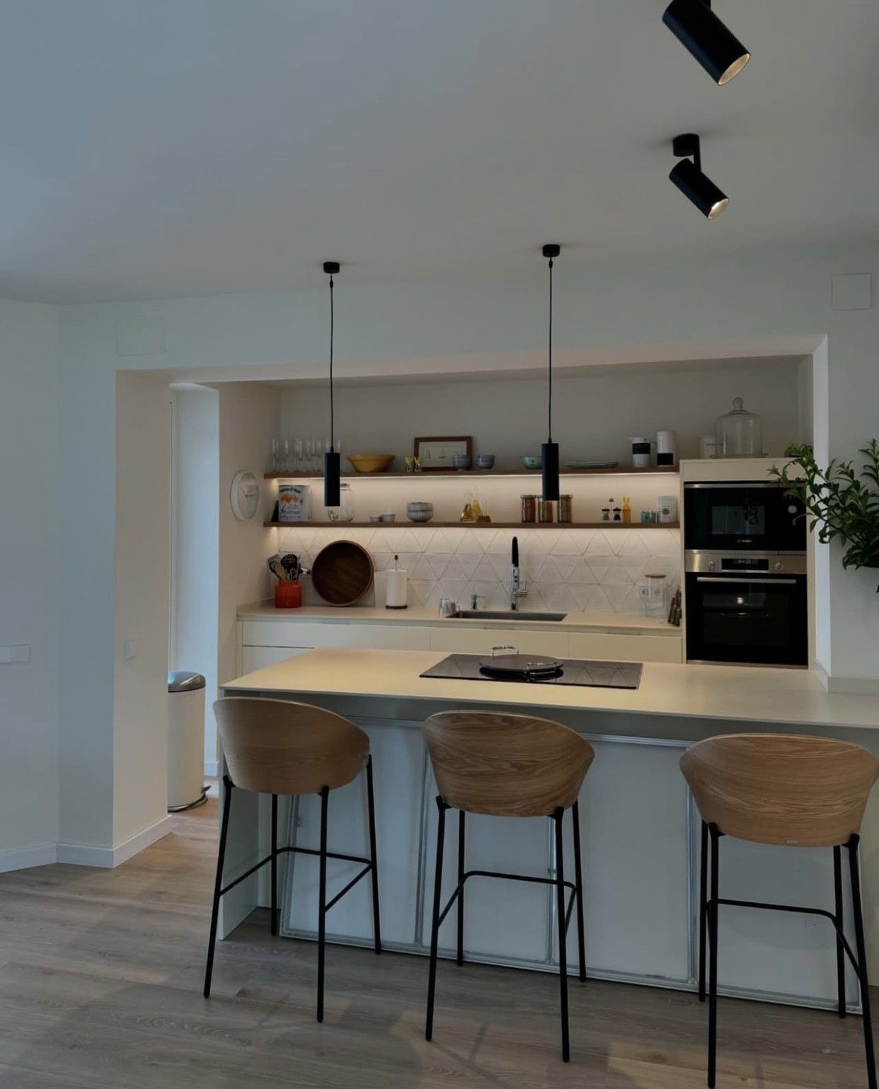 Cocina moderna con taburetes de bar. Gabinetes, encimeras y salpicadero blancos. 