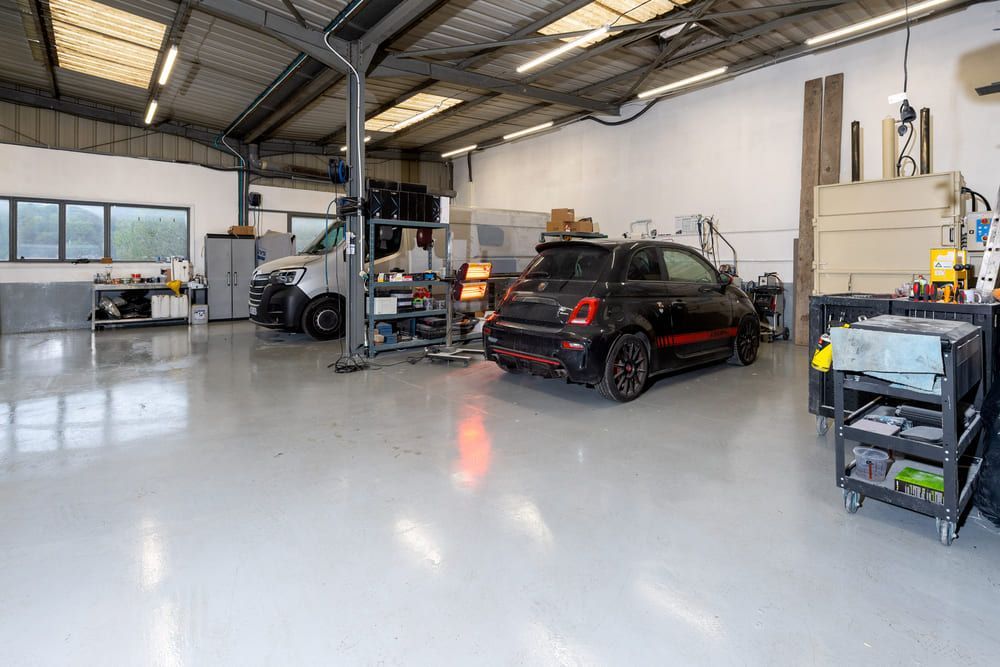 Intérieur de garage avec voiture noire et camion blanc