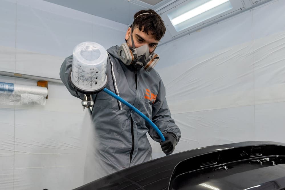 Un homme avec un masque de protection qui peint une voiture