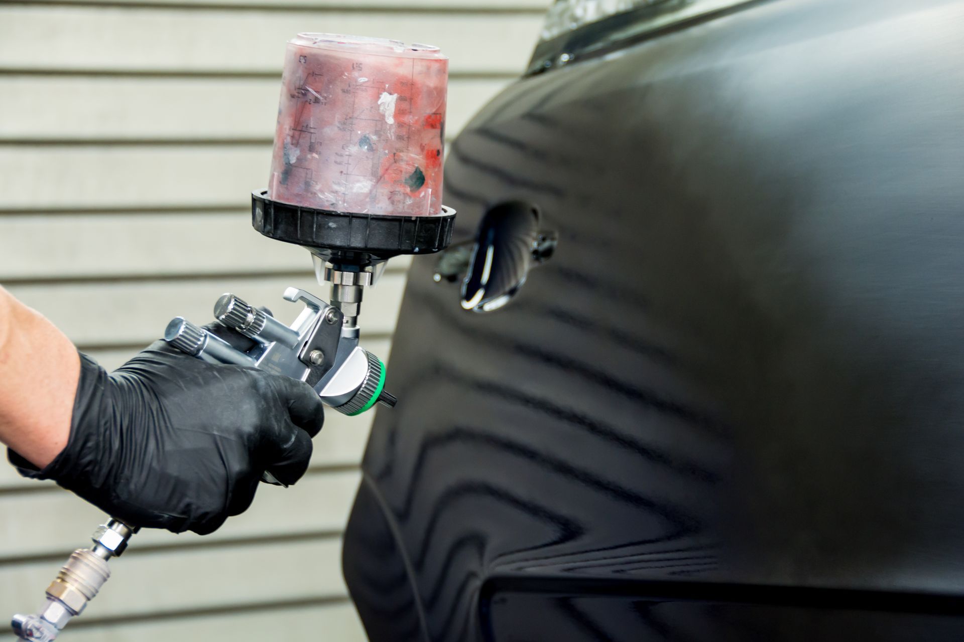 Un homme qui repeint une voiture avec de la peinture