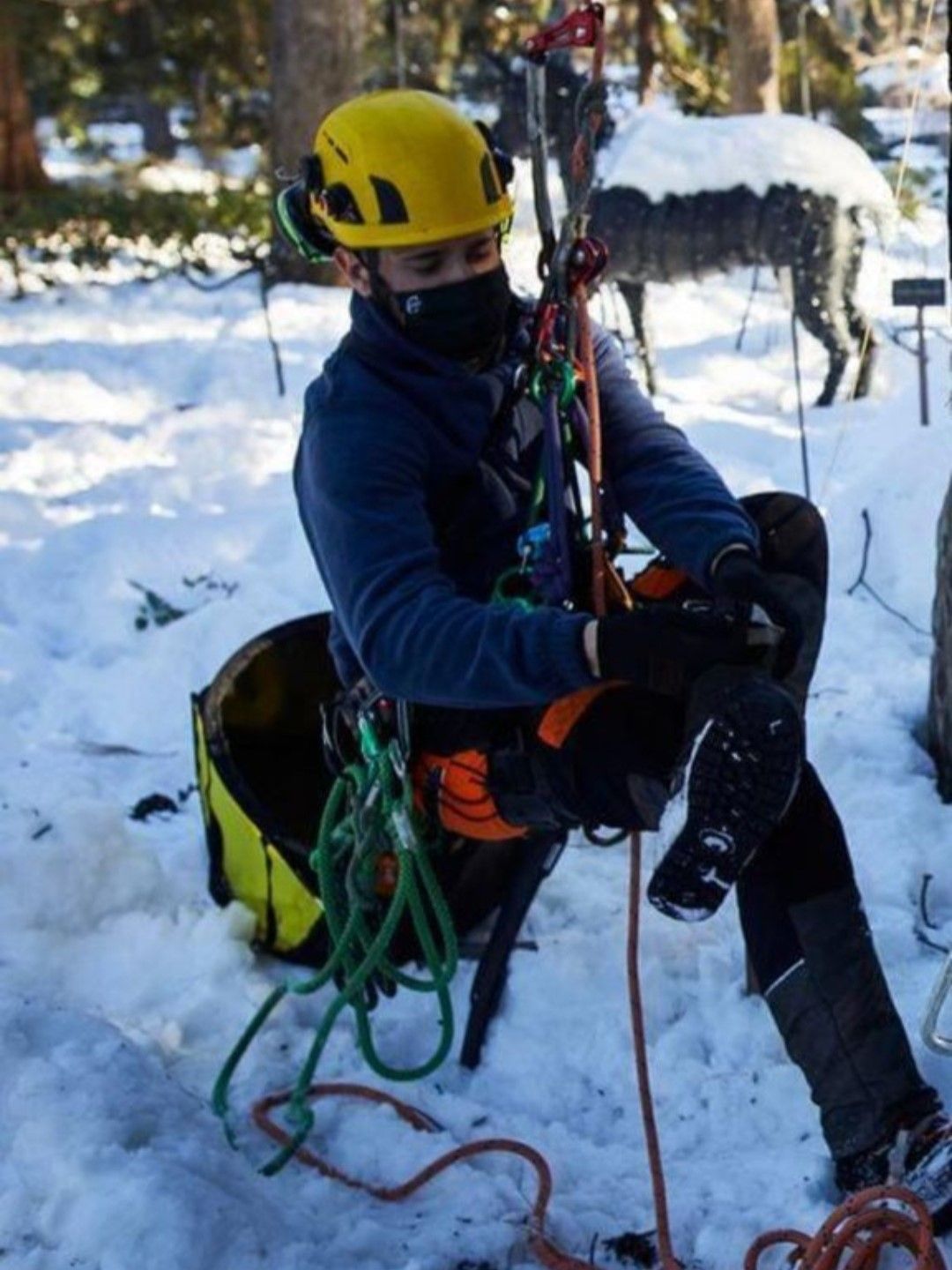 Un hombre que lleva un casco amarillo está sentado en la nieve.