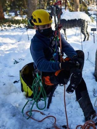 Un hombre que lleva un casco amarillo está sentado en la nieve.