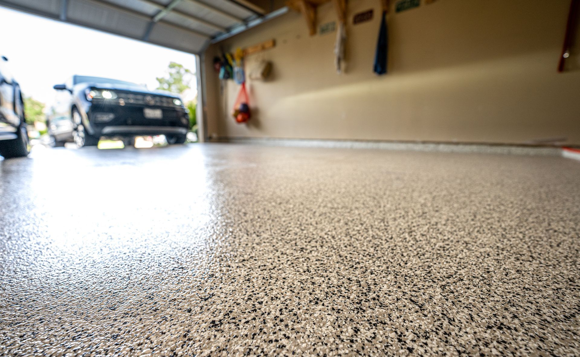 Sol de garage avec des voitures stationnées en arrière-plan et une surface texturée et brillante au premier plan.