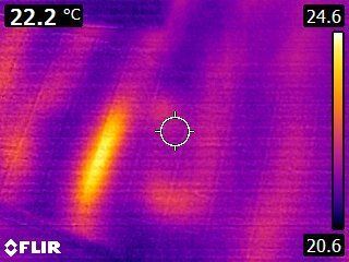 Lämpökamerakuva kirkkaasta kuumasta kohteesta violetilla taustalla, jossa on lämpötila-asteikko ja FLIR-logo.