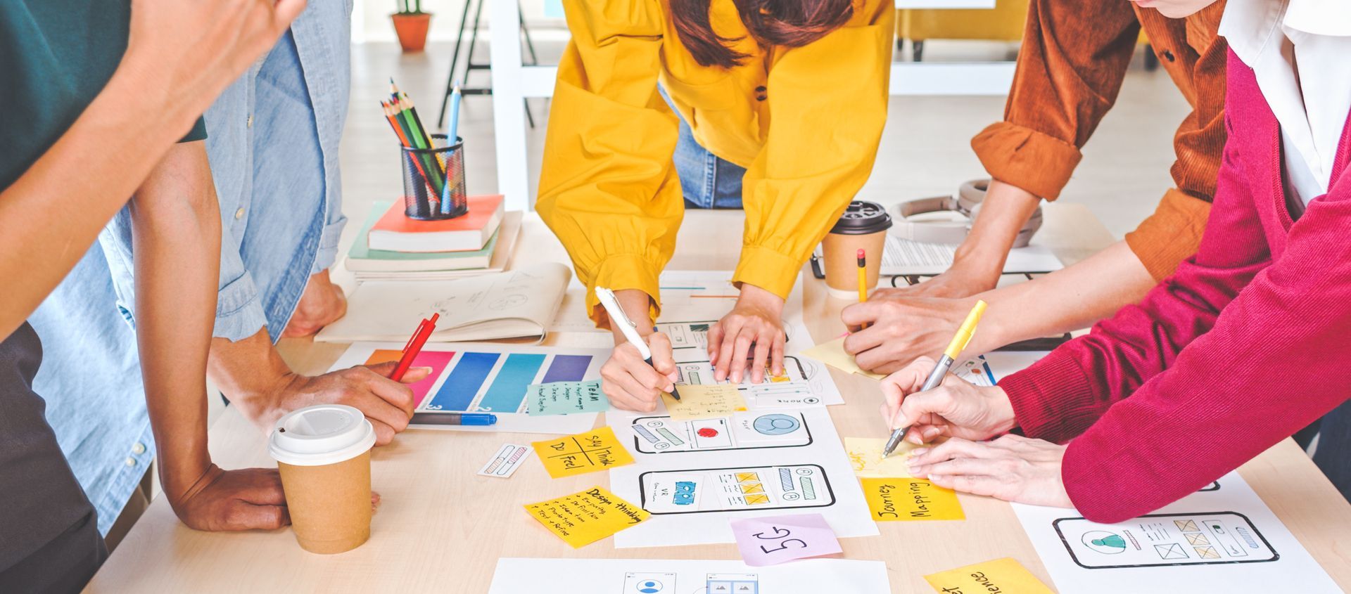 Des personnes collaborent autour d'une table, triant des cartes et des notes colorées lors d'un atelier.