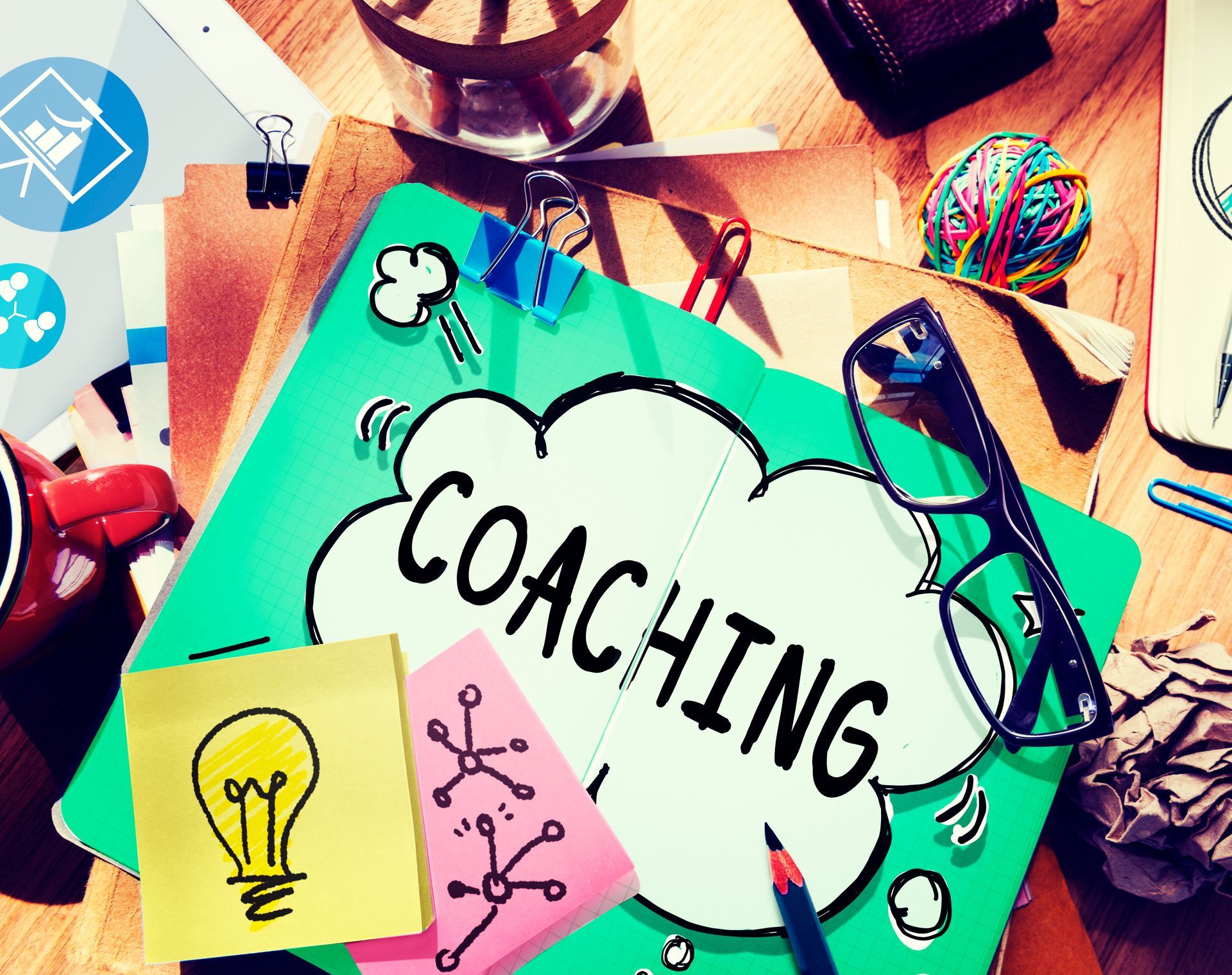 Collage illustrant le concept de coaching, avec une étiquette nuage, une note en forme d'ampoule et des objets de bureau colorés.