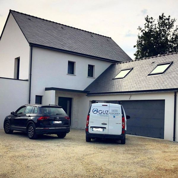Deux voitures garées devant une maison neuve