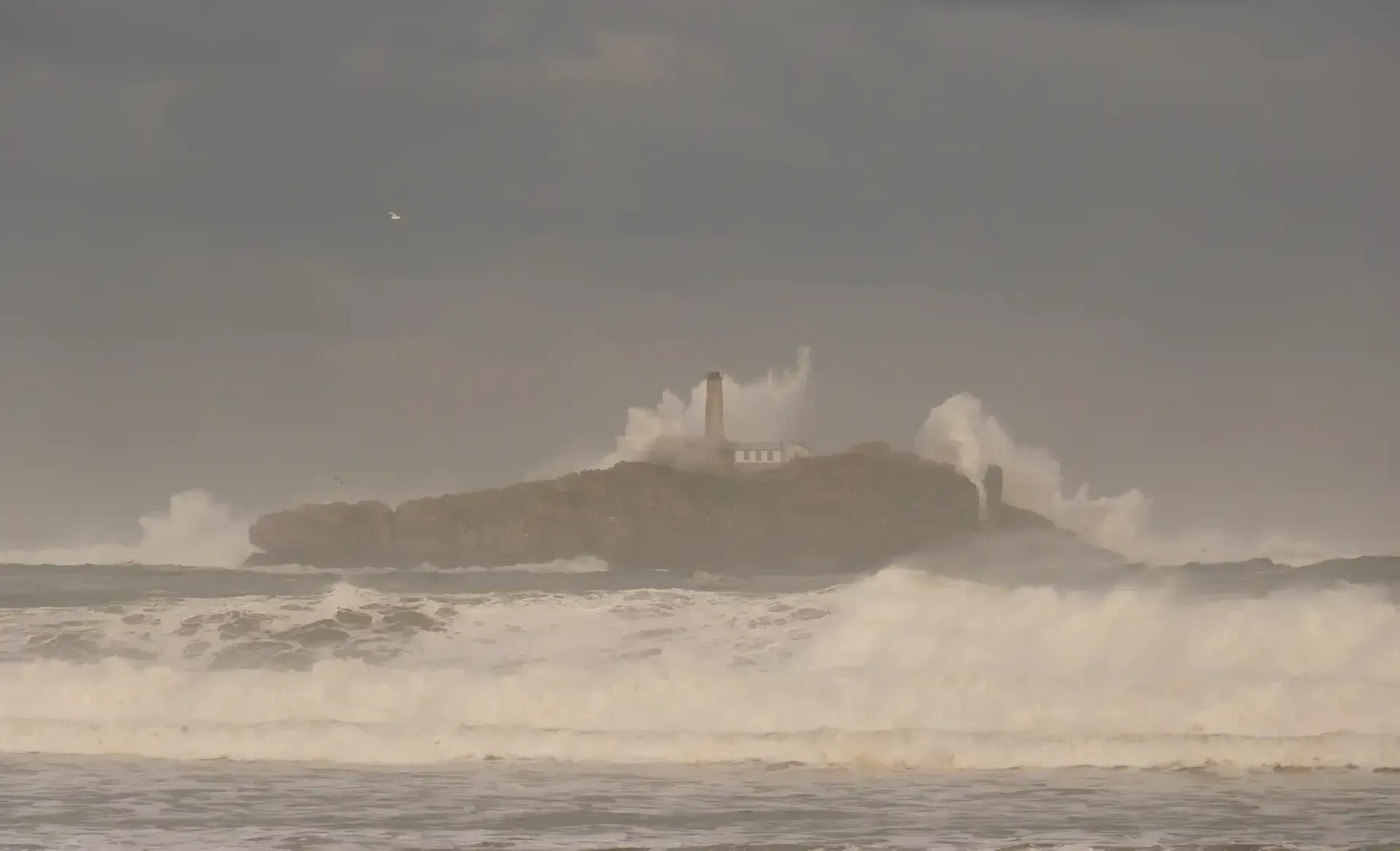 Una gran roca en medio del océano con olas rompiendo sobre ella.