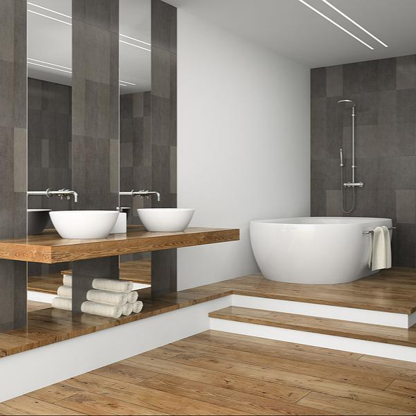 Salle de bain moderne avec baignoire ronde, double vasque sur plan en bois et carrelage mural gris.