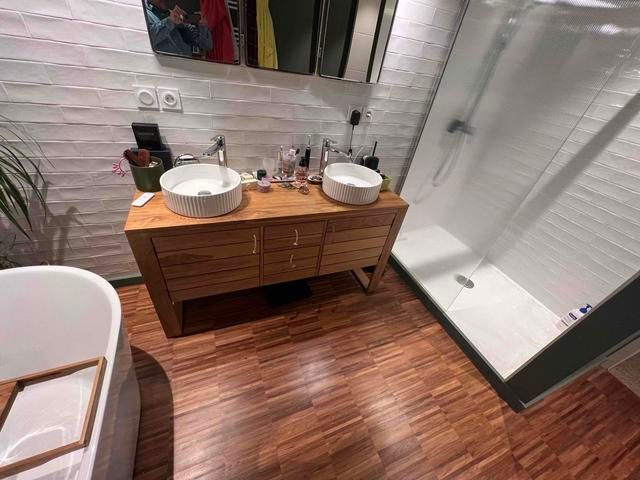 Salle de bains avec meuble-lavabo et lavabos en bois, douche en verre et baignoire îlot.