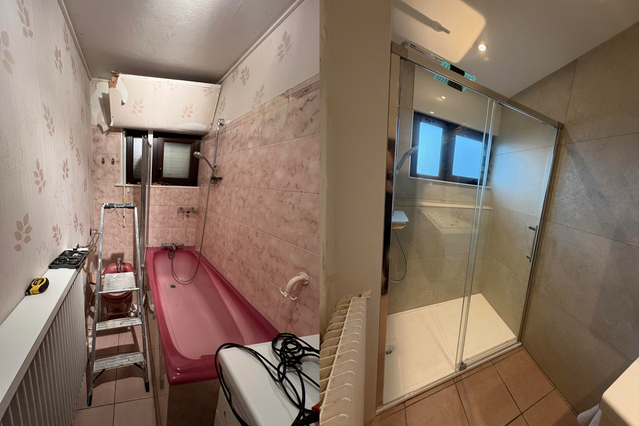 Deux photos, avant/après, d'une rénovation de salle de bains. On y voit une baignoire rouge dans l'ancien espace et une douche en verre dans le nouvel espace.