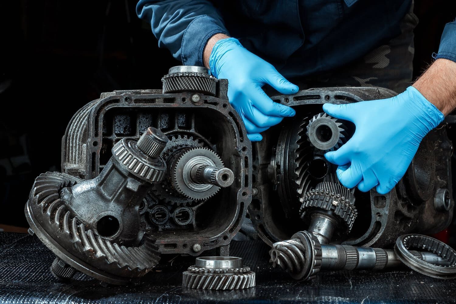 Un hombre que lleva guantes azules está trabajando en una caja de cambios.