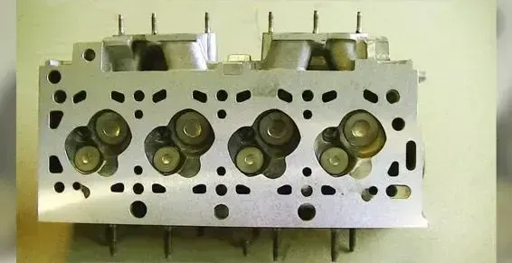 Culasse de moteur en métal blanc avec plusieurs conduits de soupape, vue de dessus