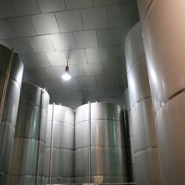 Una habitación llena de muchos tanques de acero inoxidable y una luz en el techo.