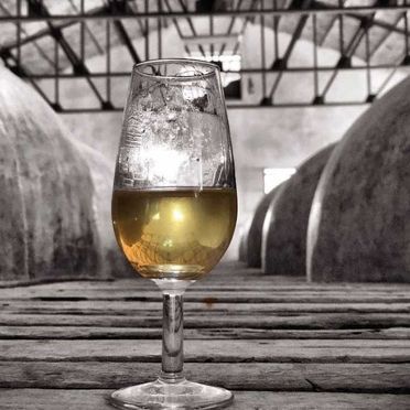 Una copa de vino está sobre una mesa de madera.