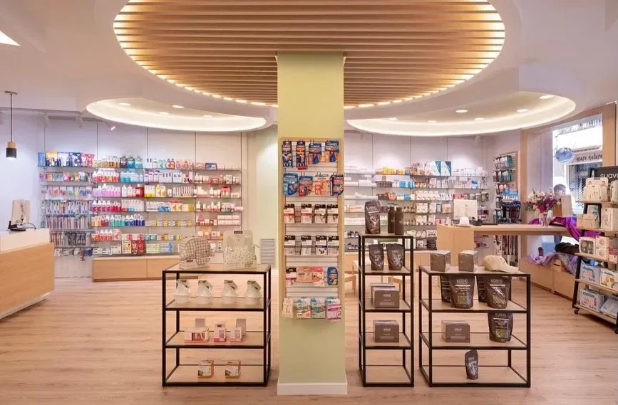 Interior luminoso de una tienda con estanterías de productos de belleza y mesas de exposición bajo luces de techo curvas.